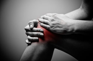 Knee pain with hands on knee. 